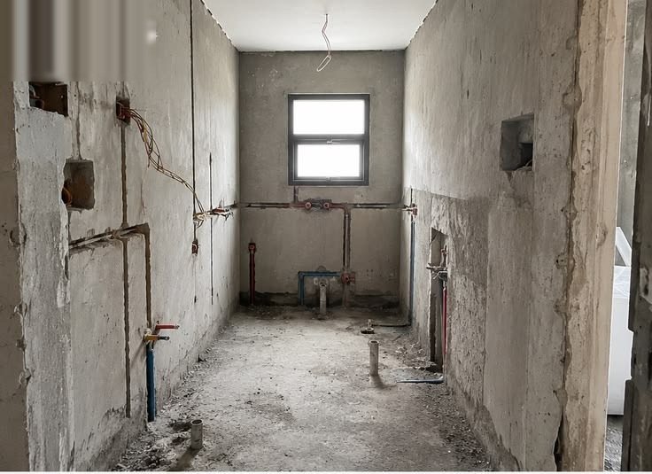 A bathroom on bare shell: exposed supply pipes and concrete walls